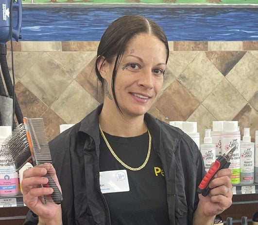 Woman with dark hair holding grooming brushes wearing black
