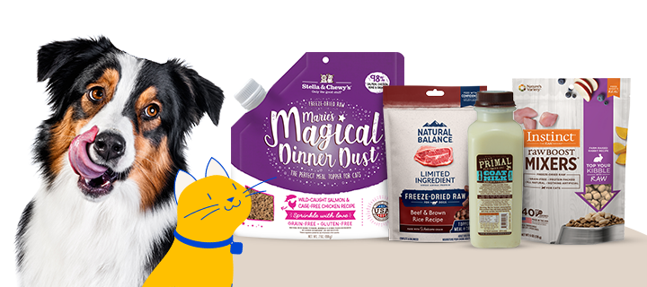 A happy dog licking its lips next to a selection of pet food products, including Stella & Chewy's "Marie&rsquo;s Magical Dinner Dust," Natural Balance freeze-dried raw, Primal goat milk, and Instinct raw boost mixers, with a yellow kitten Pet Supermarket Peticon.